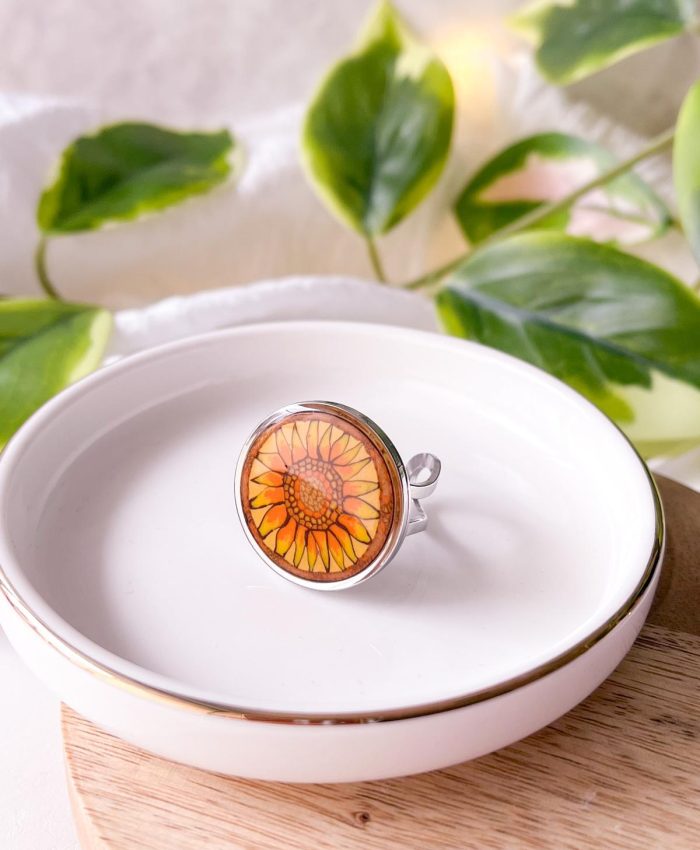 Bague avec plateau rond en acier inoxydable argenté serti avec un motif en argile polymère sur le thème du langage des fleurs : le tournesol