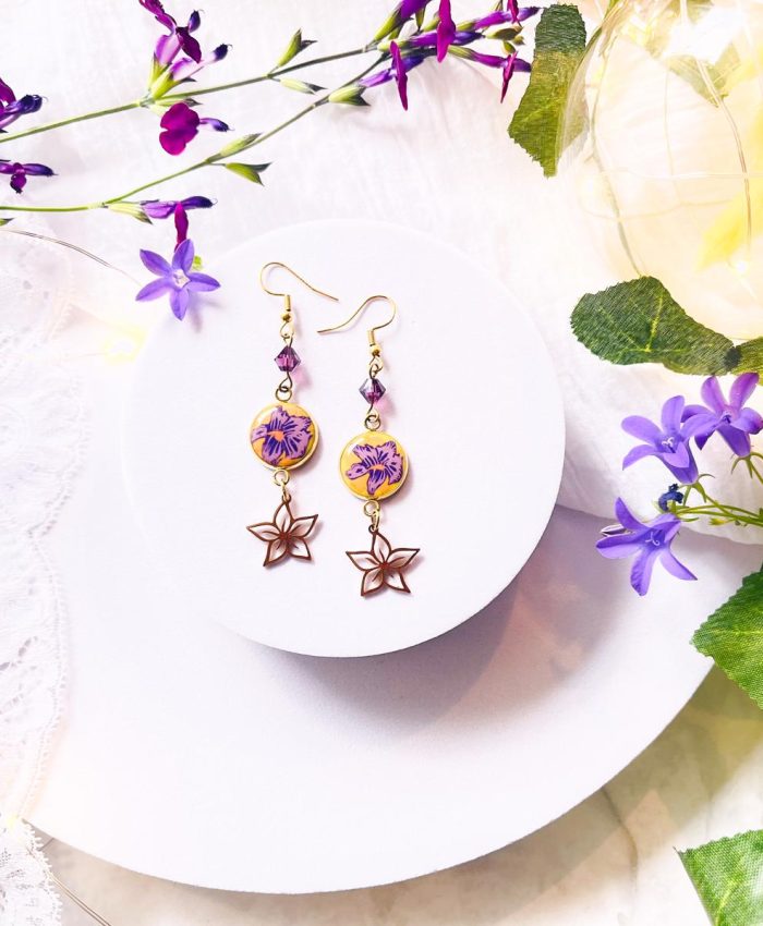 Boucles d'oreilles en acier inoxydable doré sur crochets avec médaillon serti sous résine en argile polymère fimo. Motif fleur d'iris ou de violette. Breloques en acier inoxydable doré en forme de violette