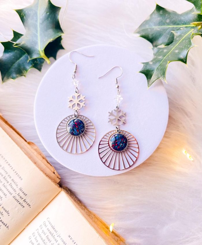Boucles d'oreilles en acier inoxydable argenté sur crochets avec médaillon serti sous résine en argile polymère fimo. Motif couleurs colométrie hiver. Breloques en acier inoxydable argenté en forme de flocon de neige et de rayons de soleil. Cristaux Swarovski blancs translucides